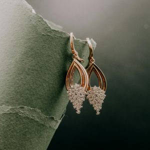 Elegant gold and diamond earrings displayed on a textured green surface highlighting luxury and style.